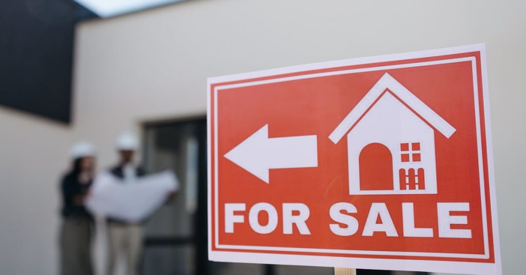 A real estate sign indicates a property for sale as two agents in hard hats discuss building plans outdoors.